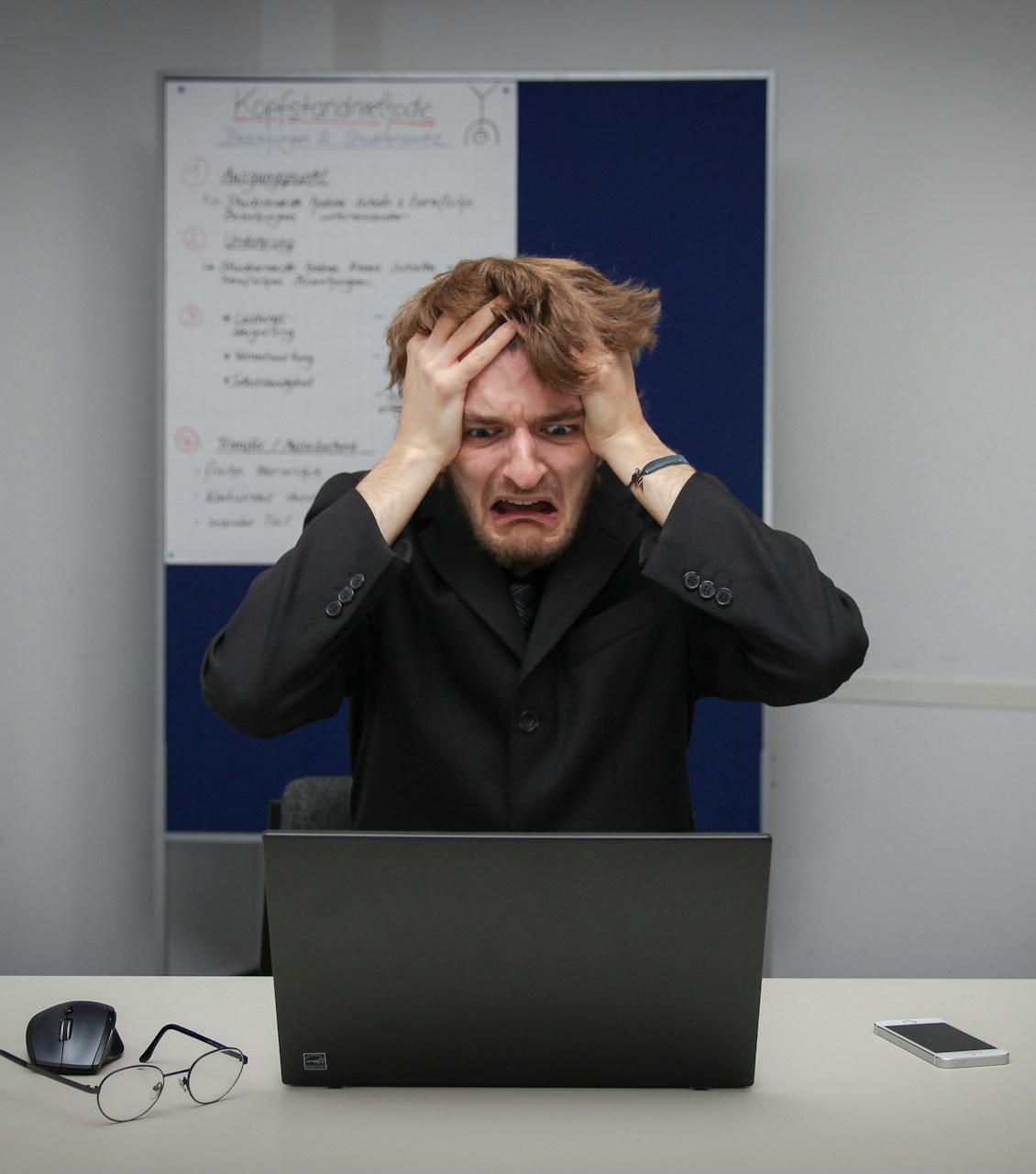 A stressed nursing student with hands on their head, staring at a laptop
